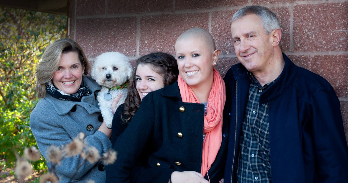 Family of four pictured in front of brick wall with pet dog, including (left to right) mother, sister, sarcoma patient and father.