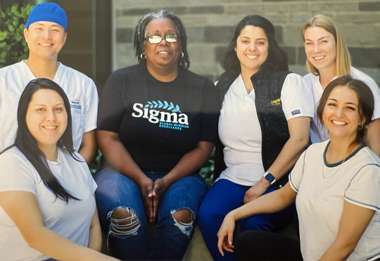 group of nursing students sitting side by side smiling at camera