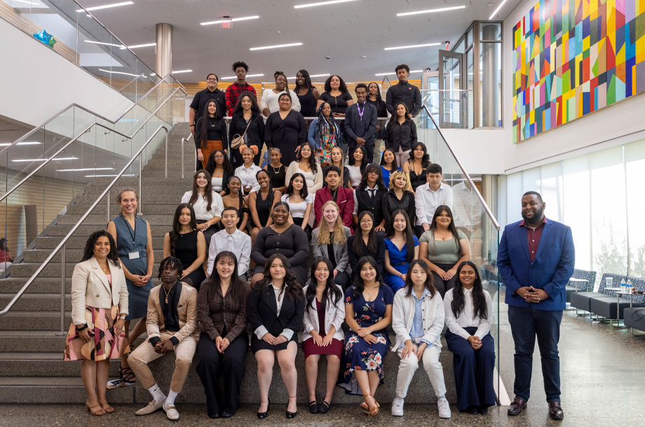 Students sit side by side ascending on a staircase and smiling