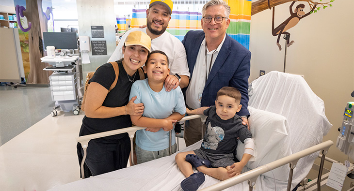 Three adults and two children pose for a photo in a hospital setting.