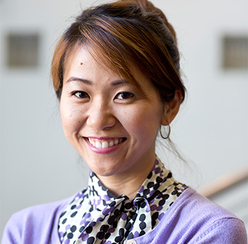 Asian American woman wearing lavender sweater and smiling into camera