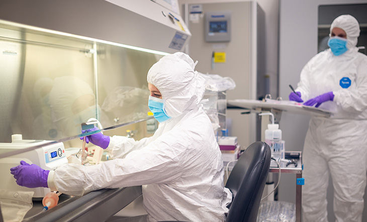 Two individuals full-geared in white protective coveralls working at UC Davis General Manufacturing Product Facility 