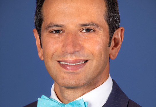 Man with black hair smiling and wearing aqua bowtie.