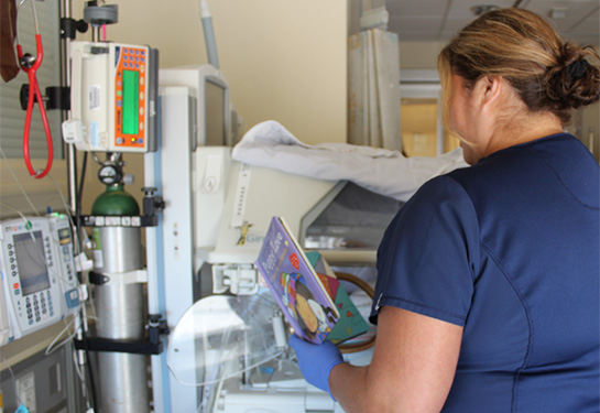 Picture of nurse in NICU with book