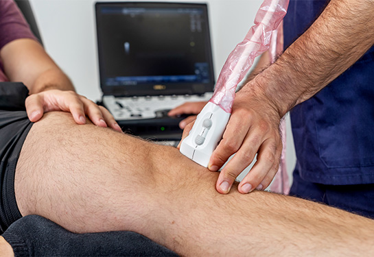 Close up of a physiotherapist performing an ultrasound of the knee
