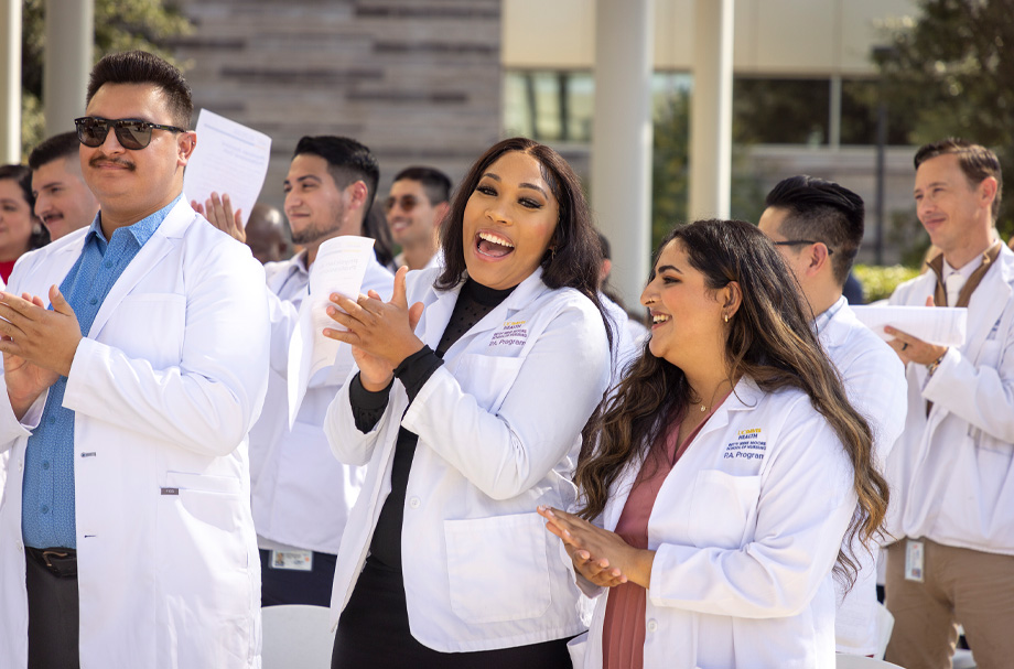 Students wearing white coats smile and clap hands