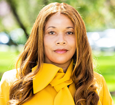 A woman wearing a bright yellow blouse smiles 