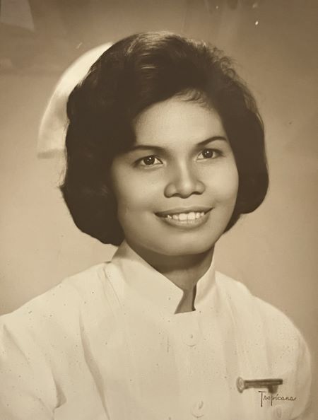 A black and white portrait of a smiling woman in a nurse’s uniform. 