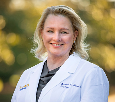 Blonde-haired woman in white coat smiling into camera