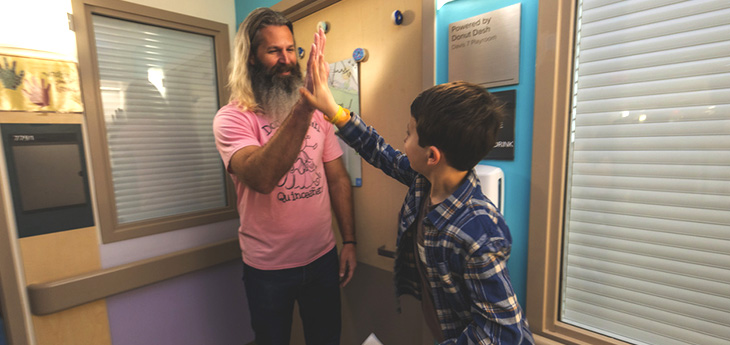 Man with beard high fives child in front of playroom