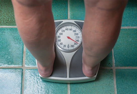 The bare feet of overweight person standing on a bathroom scale