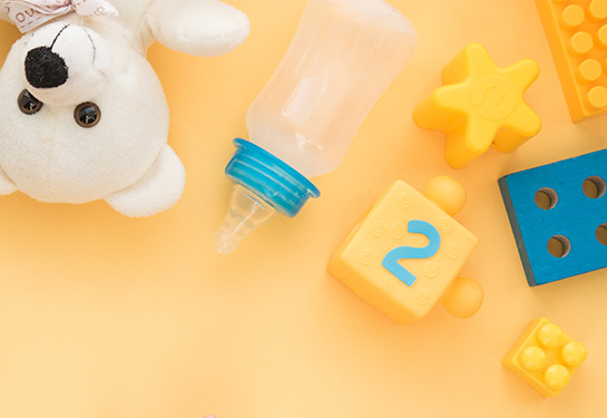 Children’s toys in white, yellow and blue colors are against a yellow background. 