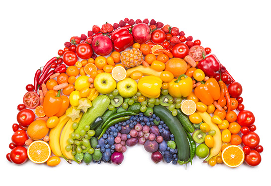 Assortment of fruits and vegetables forming the shape and colors of a rainbow