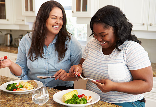 Two women smiling and eating a healthy meal