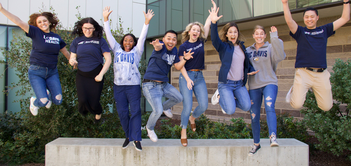 Eight nursing students in mid-air jumping off a bench