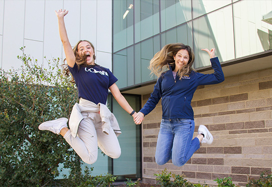 Two nursing students in mid-air jumping off a bench