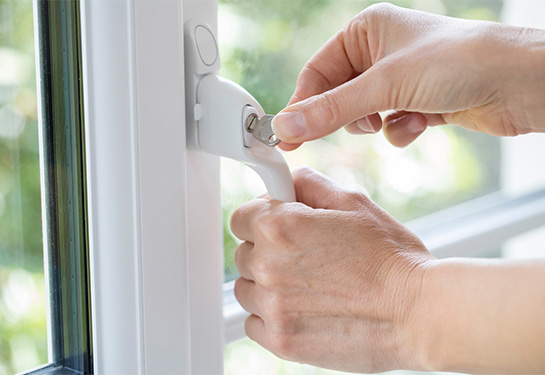 Hand of person using key to lock window handle 