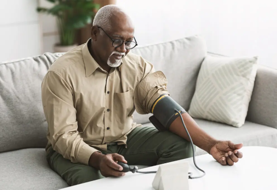 Active senior man measuring his blood pressure in living room