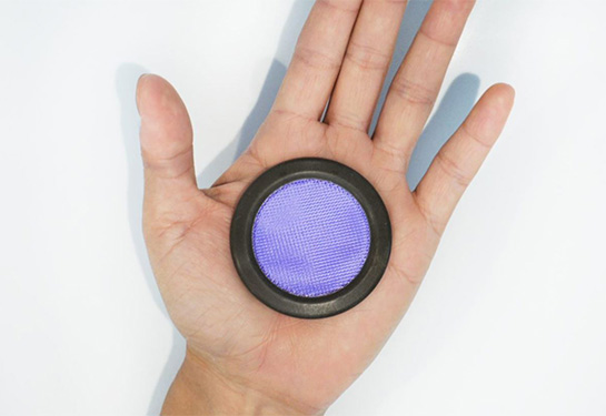 Round device that is purple in the middle and black on the outside rim sits on a person&#x2019;s palm.