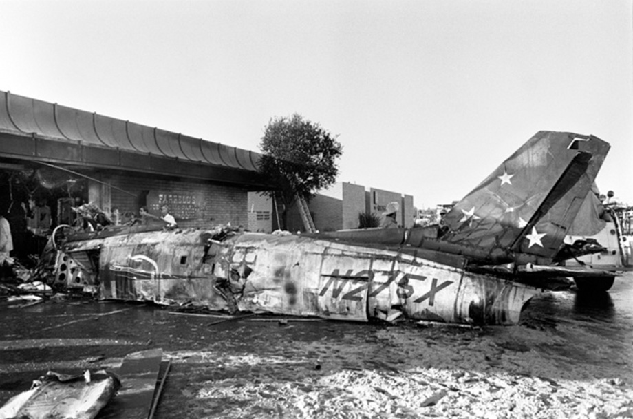 Archived photo of burned plane  on ground after crashing into ice cream parlor building