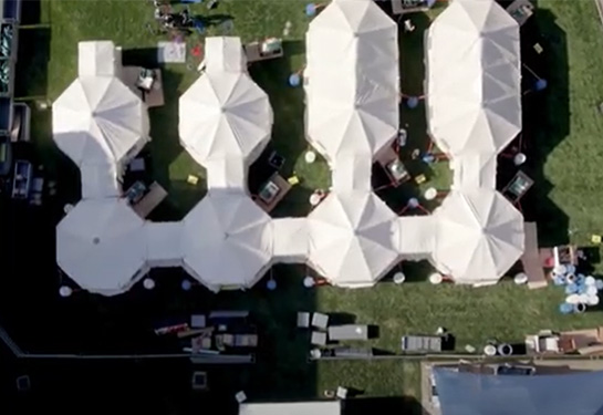 Aerial view of white tents in four rows-connected at the bottom of the picture