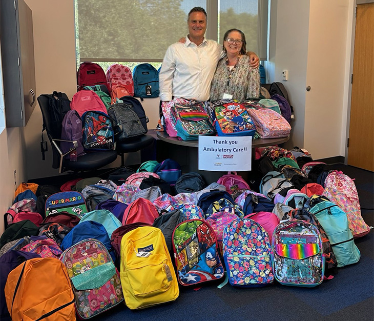 Man and woman stand behind a room full of backpacks