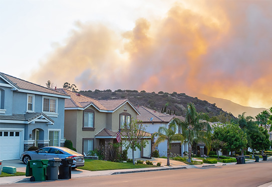 Row of residential houses along street with hill in the background on fire