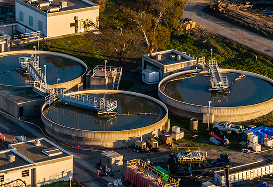 An aerial view of a water treatment plant featuring three large water storage tanks