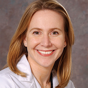 A close-up of Dr. Aimee Moulin smiling. She is wearing her white coat.