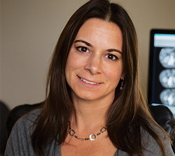 A female with long dark hair sitting with her back to a computer screen