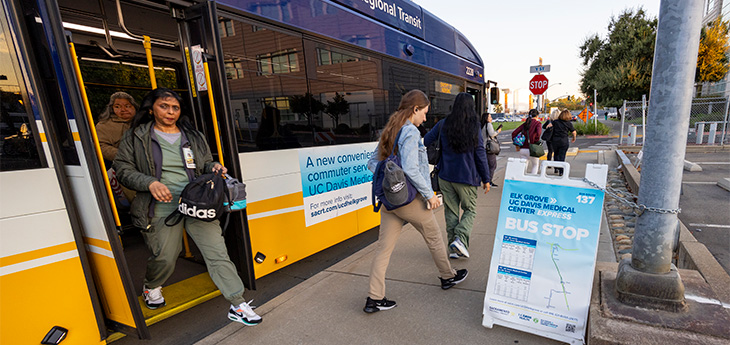 Woman exiting the back of a Sacramento Regional Transit bus as others walk away from the bus. 