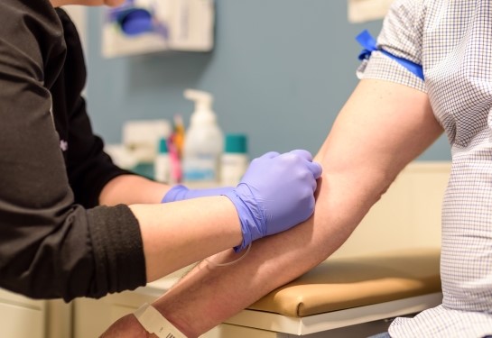 Male nurse holding man&#x2019;s finger to check his blood sugar