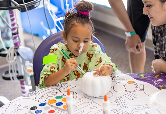 Young girl painting a pumpkin