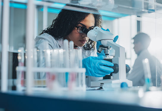 Female scientist looking through a microscope in a lab