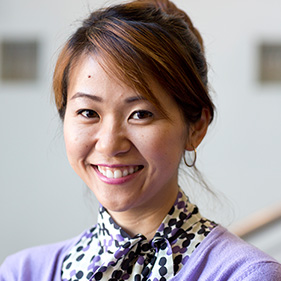 Woman wearing lavender sweater with dark hair pulled back.