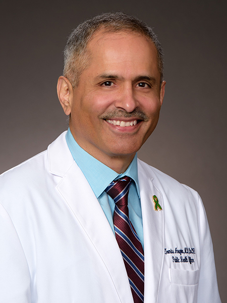 Studio portrait of smiling man wearing white lab coat, over a light blue shirt and red tie