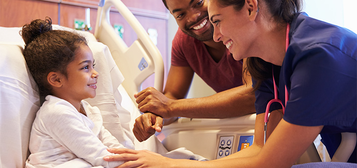 Child in a hospital bed with dad and medical person 