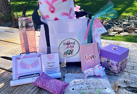 White tote bag with “Harvest4Pink” logo and an array of items including pillow, cards, box and inspirational sayings.