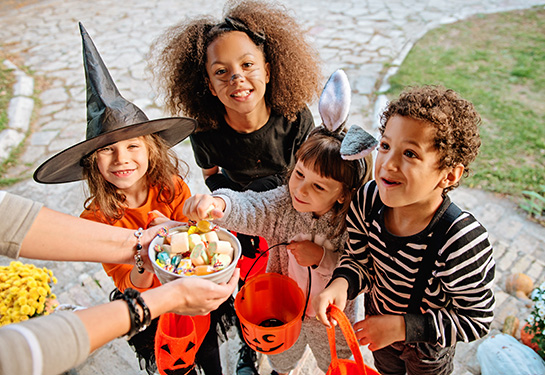 Children in Halloween costumes trick or treating at house