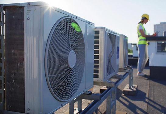 Construction worker stands near air conditioning systems.