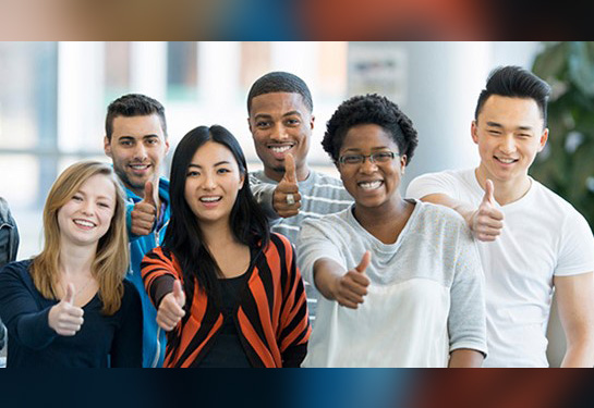 A group of people smiling and holding thumbs up.