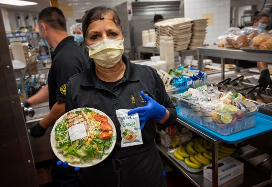 A Food and Nutrition Services team member poses with a packaged meal.