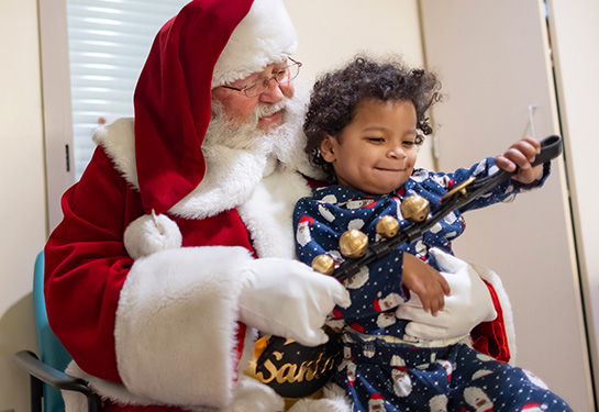 Child playing with a toy while sitting on Santa's lap