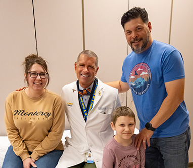 Three adults and a child pose for a picture in an exam room.