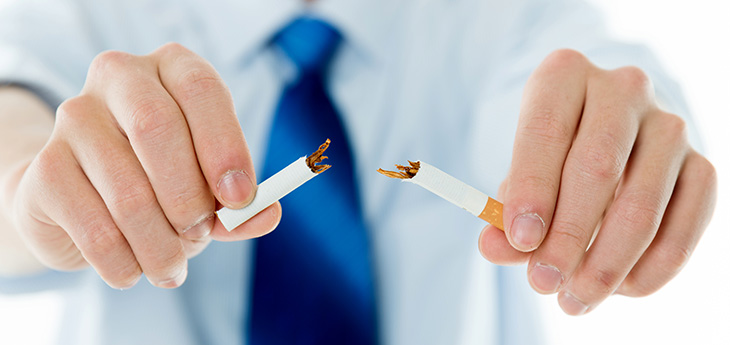Hands against a background of a white shirt and blue tie breaking a cigarette in half