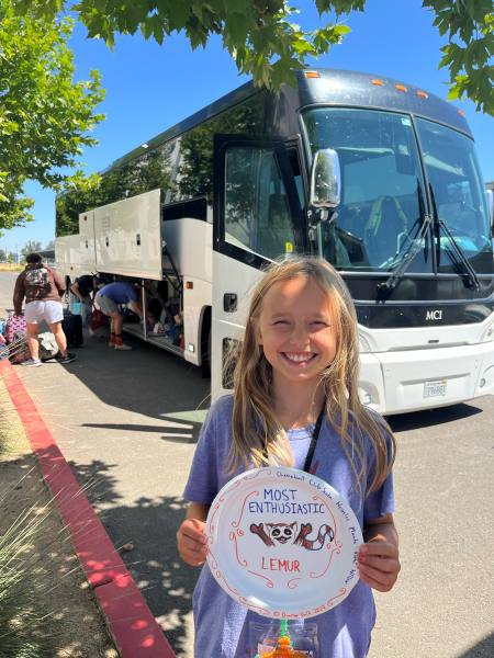 Blonde girl smiling with a paper plate sign that reads 