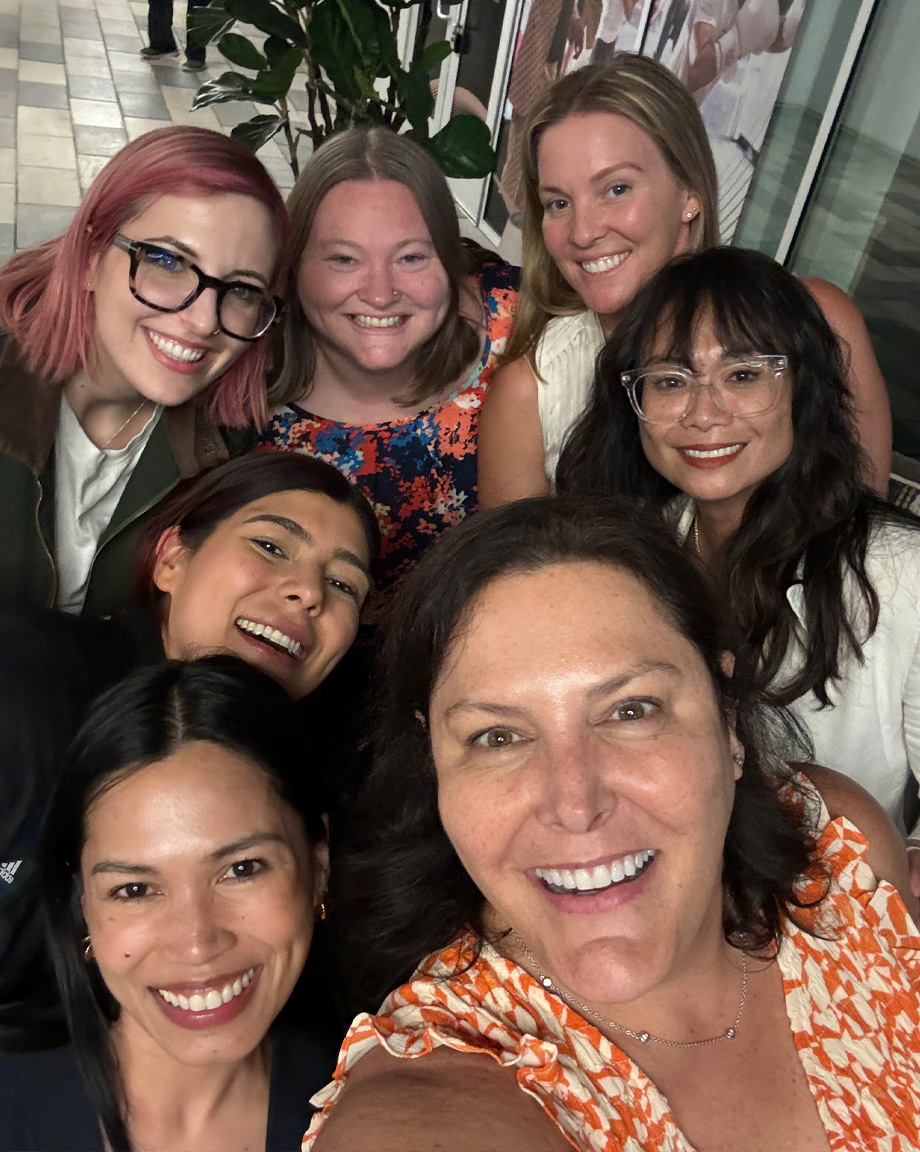 Seven women in tight group smiling at camera in selfie