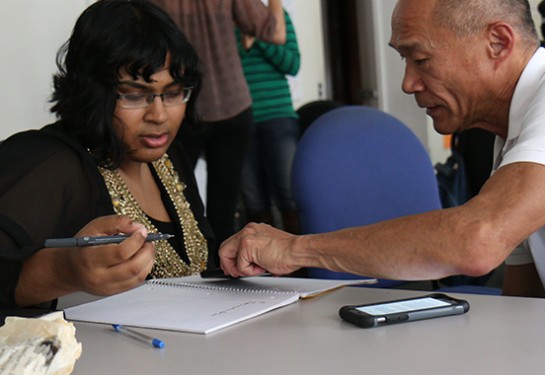 two people writing in notebook