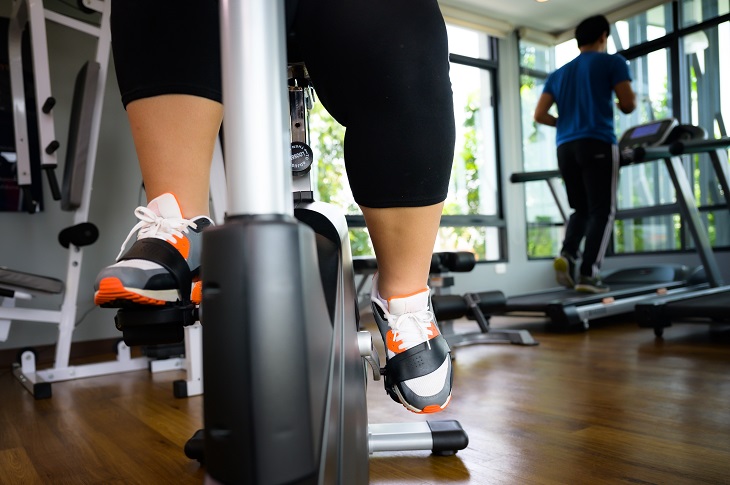 An overweight individual cycling in a gym.