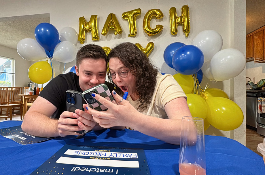 Two medical students react happily as they view their cell phones to learn they matched together at UCSF